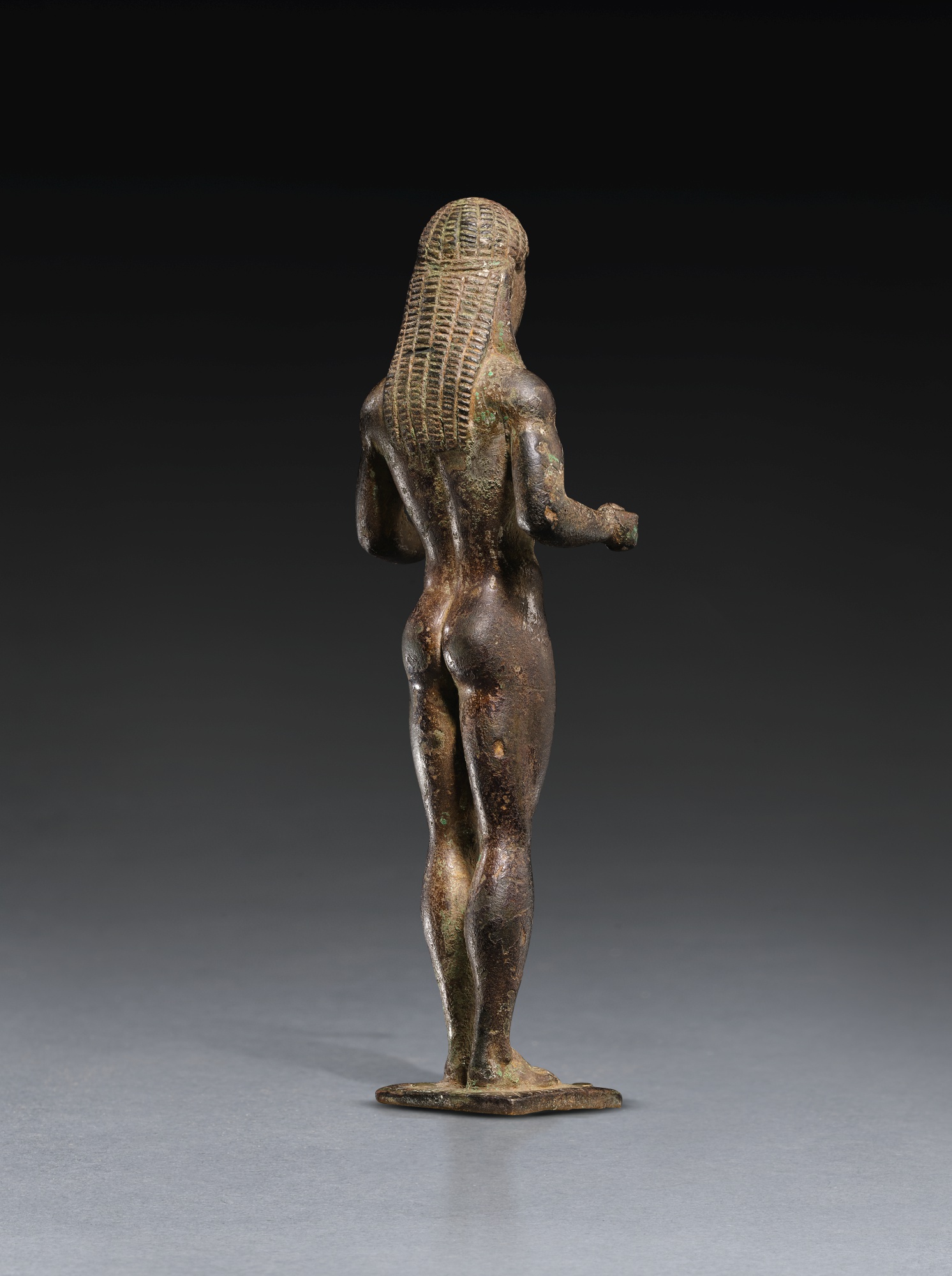 A GREEK BRONZE FIGURE OF A KOUROS DEDICATED TO APOLLO, LACONIAN, MID