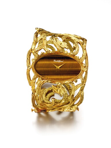 View full screen - View 1 of Lot 48. BUECHE GIROD | AN UNUSUAL YELLOW GOLD CUFF WATCH WITH TIGER'S EYE DIAL CIRCA 1975.
