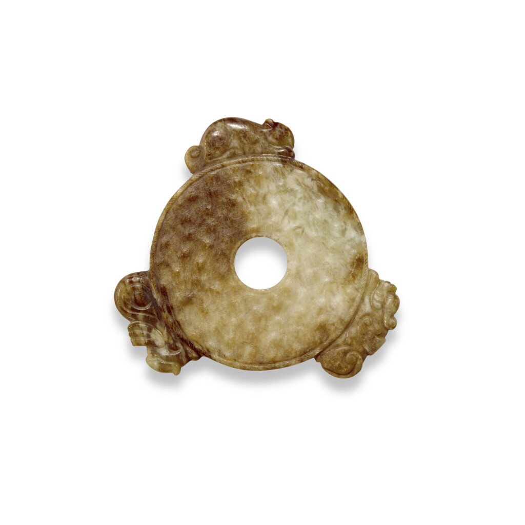 View full screen - View 1 of Lot 85. A small archaistic brown and celadon jade disc (Bi), Six Dynasties .