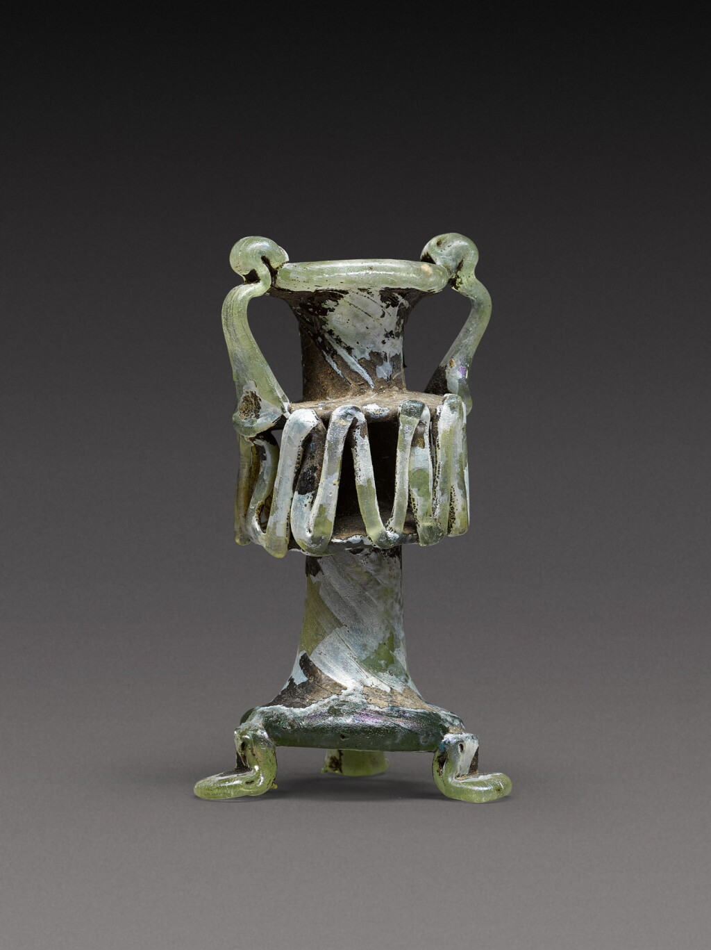 View full screen - View 1 of Lot 8. A Roman Green Glass Unguentarium, circa 4th century A.D..