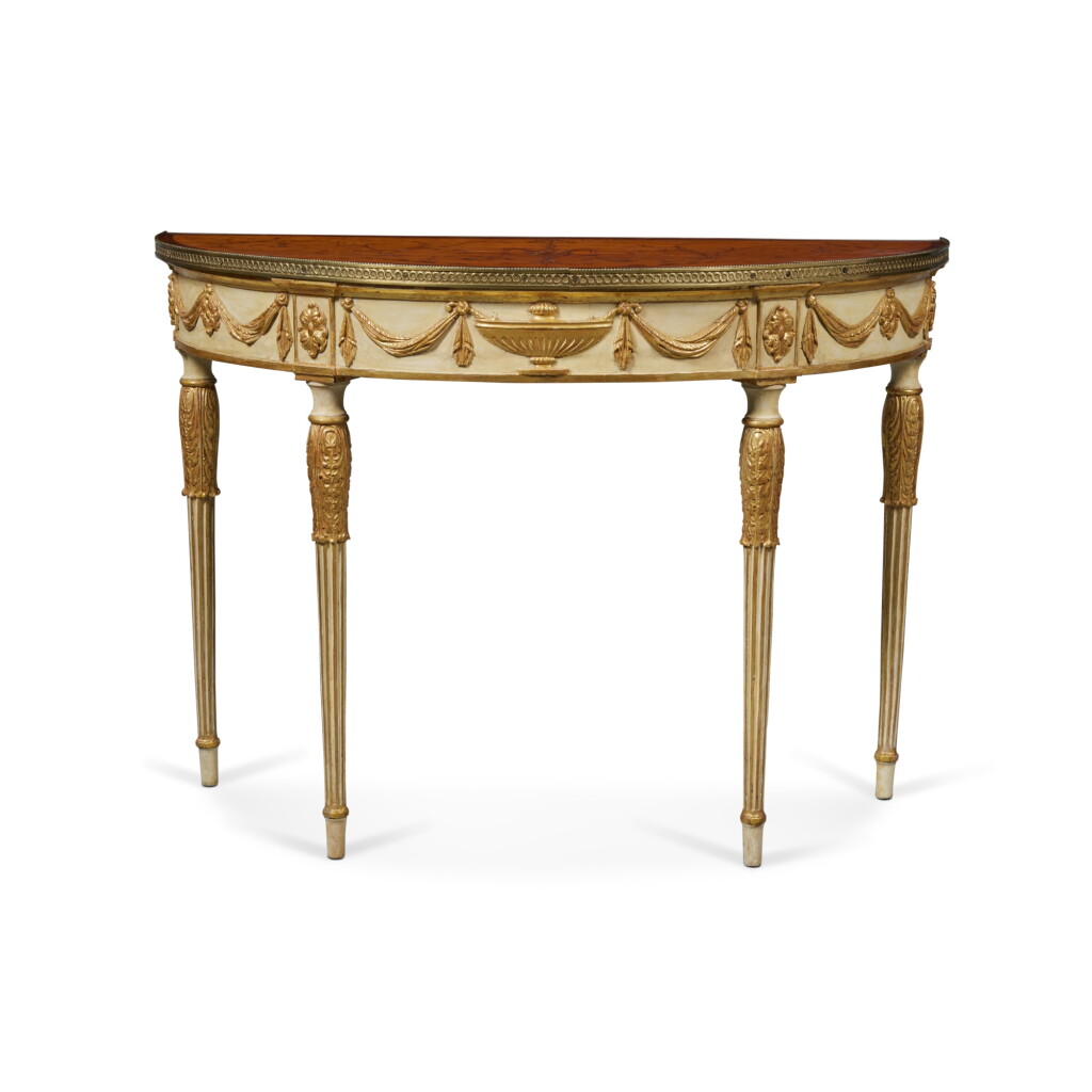 View full screen - View 1 of Lot 402. A George III Gilt-Metal Mounted Satinwood Marquetry and Rosewood Crossbanded Cream-Painted and Parcel-Gilt Demilune Console Table, Circa 1780.