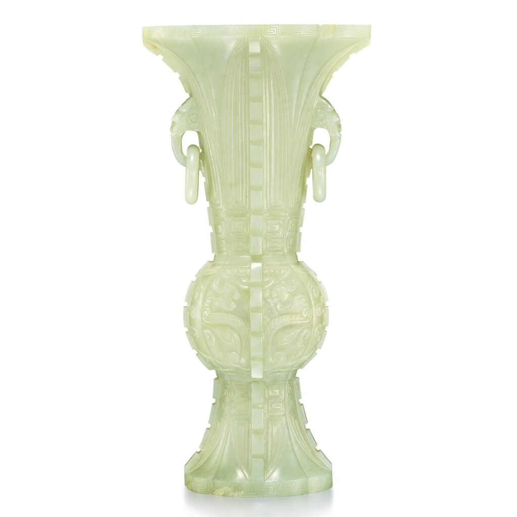 View full screen - View 1 of Lot 27. An archaistic celadon jade gu-form vase, 20th century | 二十世紀 青玉雕仿古饕餮紋獸耳活環出戟海棠式花觚.