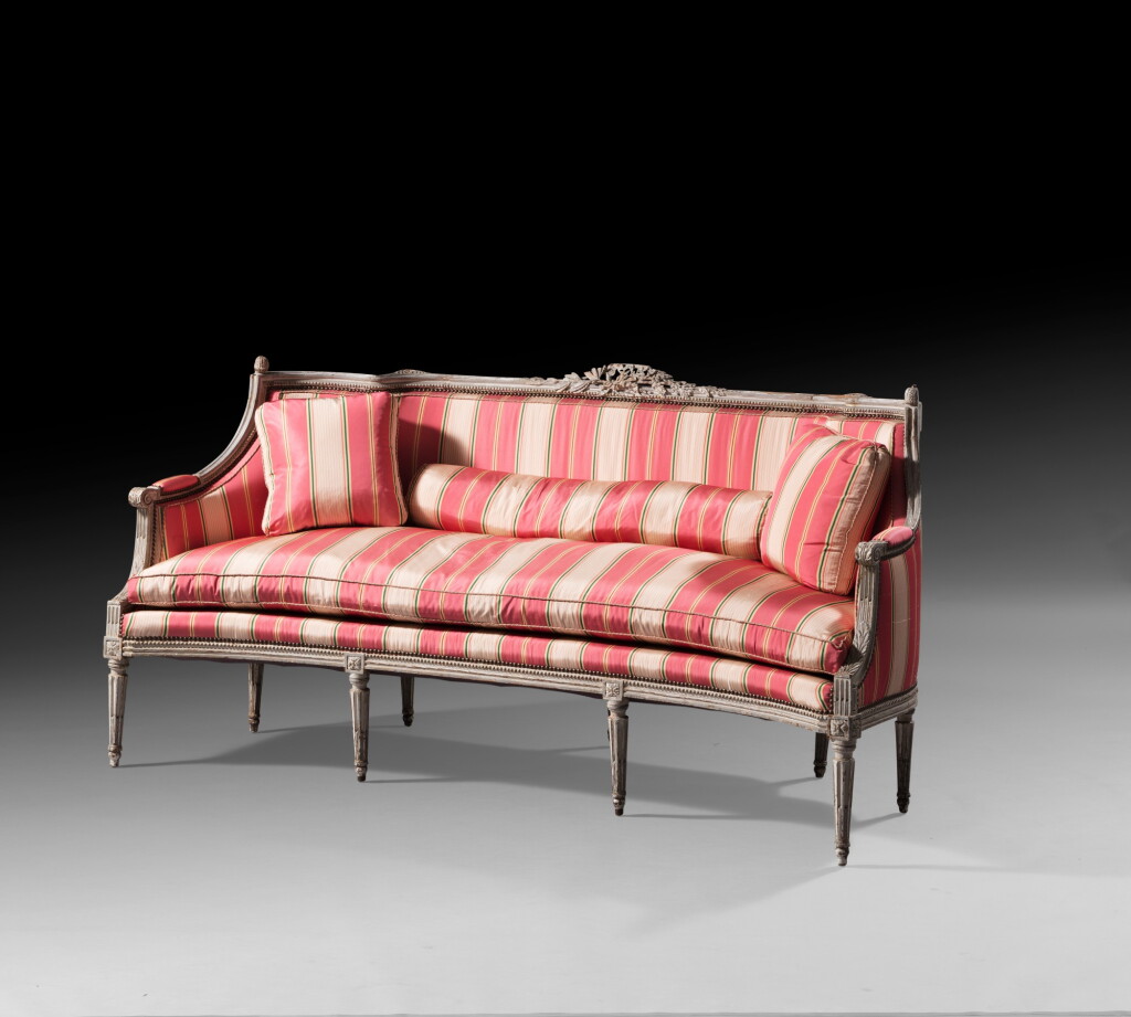 View full screen - View 1 of Lot 135. A carved and cream painted canapé, Louis XVI | Canapé d'alcôve en bois laqué crème d'époque Louis XVI.