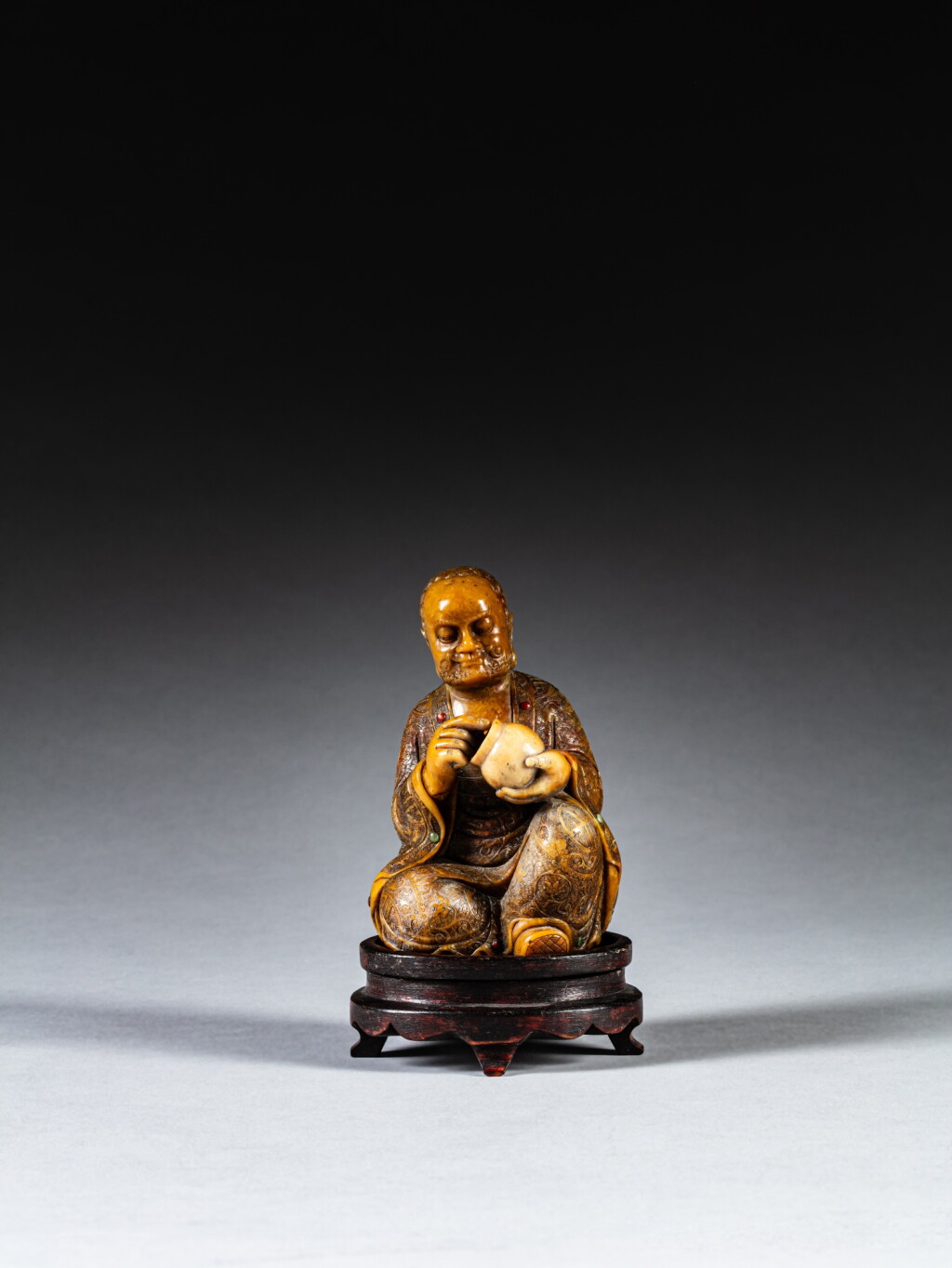 View full screen - View 1 of Lot 212. A carved soapstone figure of a Luohan, Qing dynasty, 18th / 19th century | 清十八 / 十九世紀 壽山石雕羅漢坐像.