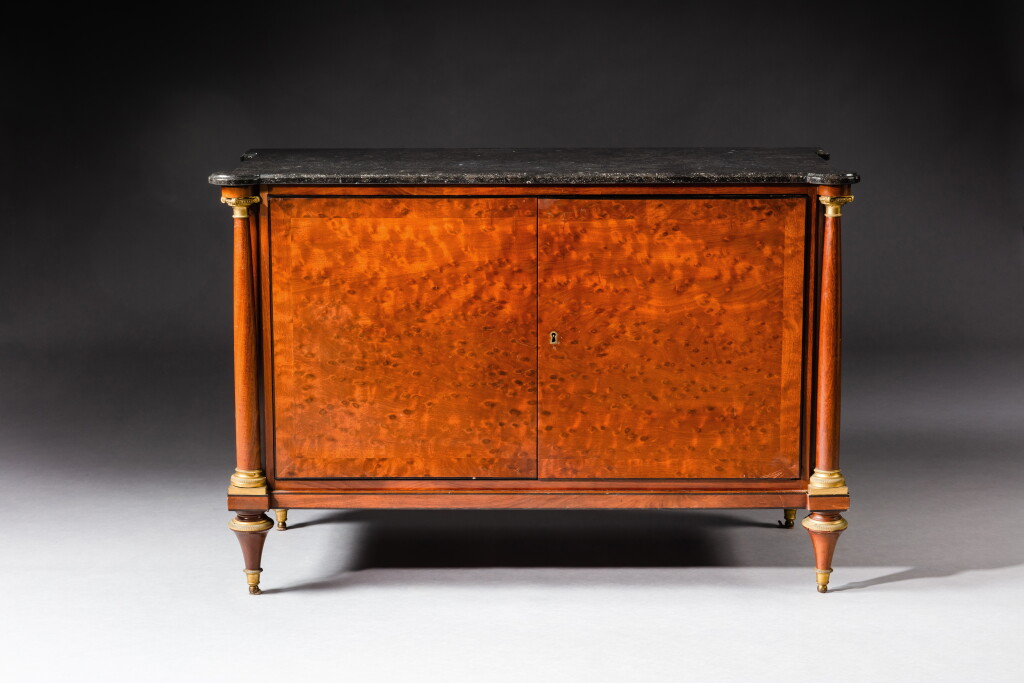 View full screen - View 1 of Lot 445. A Louis XVI gilt-bronze mounted plumpudding mahogany commode "à portes", in the manner of Adam Weisweiler, late 18th-early 19th century | Commode en placage d'acajou moucheté et monture de bronze doré, de la fin du XVIIIe-début XIXe sicèle, à la manière d'Adam Weisweiler.