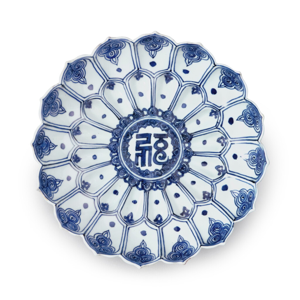 View full screen - View 1 of Lot 86. A molded blue and white 'lotus' dish, Mark and period of Wanli | 明萬曆 青花花卉梵文蓮式盤 《大明萬歷年製》款.