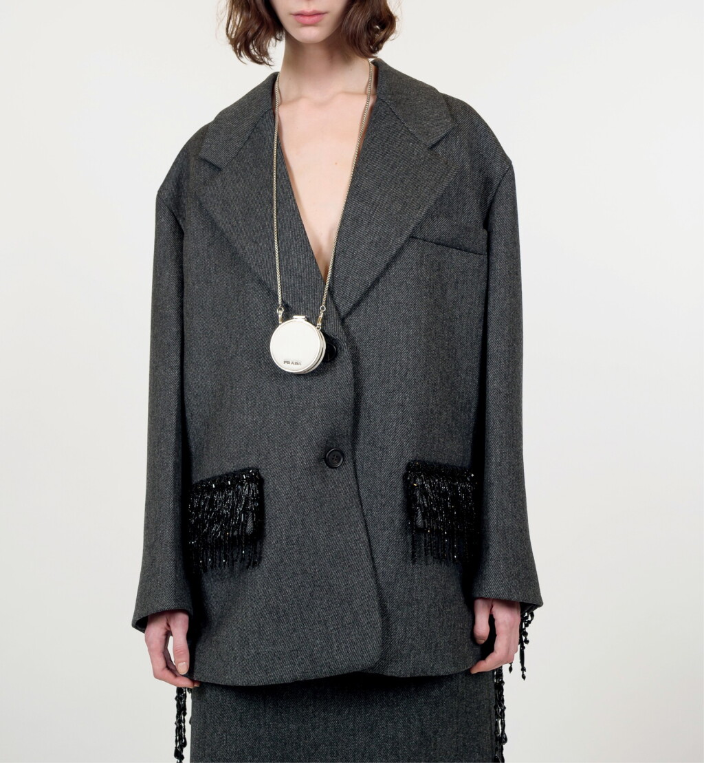 View full screen - View 1 of Lot 30. PRADA | BEADED FRINGES WOOL CABAN JACKET, WOOL SKIRT, VANITY NECKLACE, METAL HEADBAND AND LEATHER PUMPS WITH EMBROIDERED GAITER. UNIQUE LOOK (EXCEPT HEADBAND) NOT IN THE STORES.