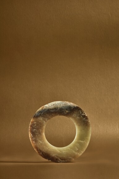 View full screen - View 1 of Lot 83. An archaic pale green and brown jade disc (Huan), Neolithic period, Qijia culture .