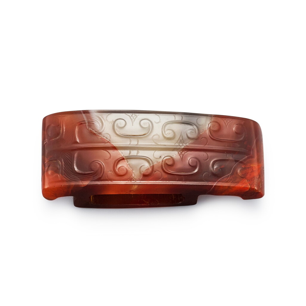 View full screen - View 1 of Lot 546. An agate 'beast mask' scabbard slide Western Han dynasty | 西漢 瑪瑙獸面紋劍璏.