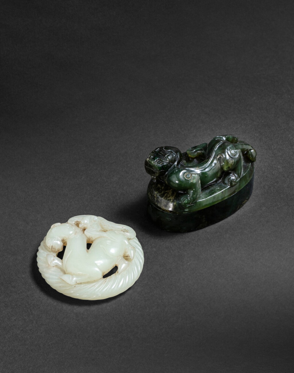 View full screen - View 1 of Lot 168. Pendentif en jade céladon et boîte couverte en jade vert épinard Fin de la dynastie Qing | 清晚期 青白玉牌及翠玉蓋盒 | A spinach-green jade 'chilong' box and cover and a pale celadon jade 'horse'pendant, late Qing Dynasty.