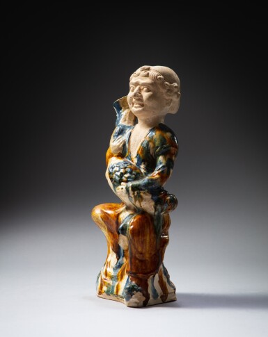 View full screen - View 1 of Lot 56. A sancai-glazed figure of a foreigner holding a 'goose' wine vessel, Tang dynasty | 唐 三彩藍釉抱鵝壺俑.
