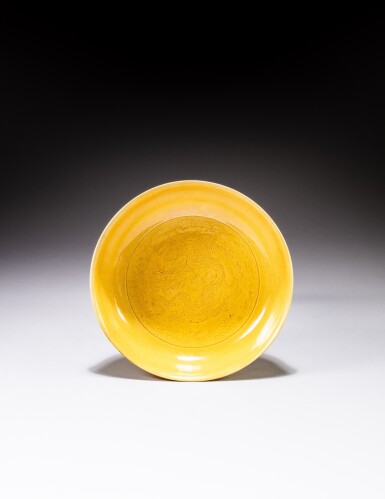 View full screen - View 1 of Lot 109. A yellow-glazed incised 'dragon' dish, Mark and period of Kangxi | 清康熙 黃釉暗刻雲龍紋盤《大清康熙年製》款.