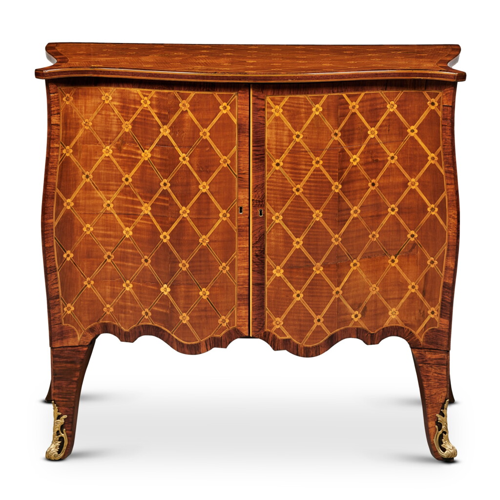 View full screen - View 1 of Lot 399. A George III Serpentine Harewoood And Marquetry Two-Door Commode, In the Manner of John Cobb, Circa 1770.