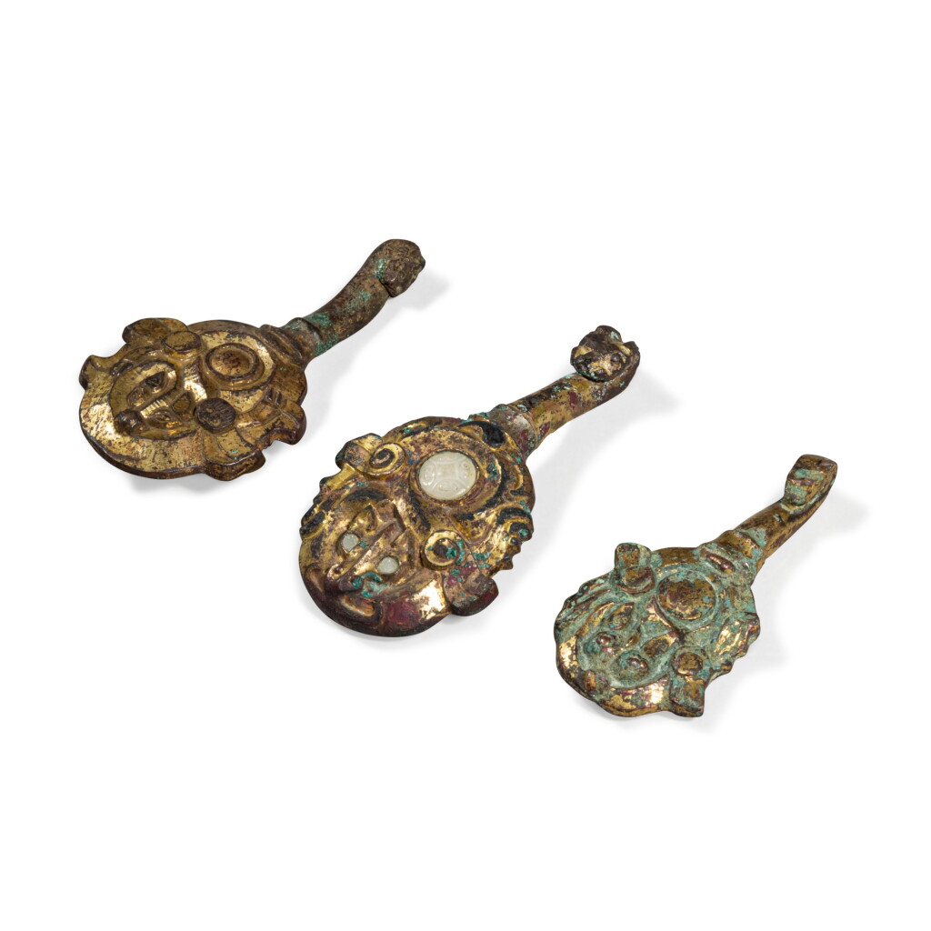 View full screen - View 1 of Lot 887. A group of three gilt-bronze belt hooks, Han dynasty | 漢 銅鎏金帶鉤一組三件.