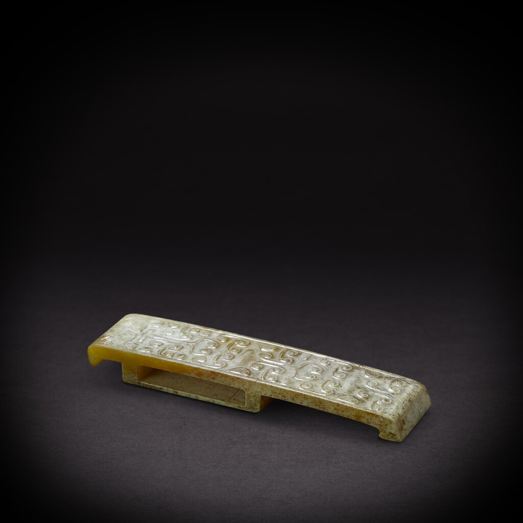 View full screen - View 1 of Lot 6844. A yellowish-celadon jade 'mask' scabbard slide, Western Han dynasty | 西漢 青黃玉獸面紋劍璏.