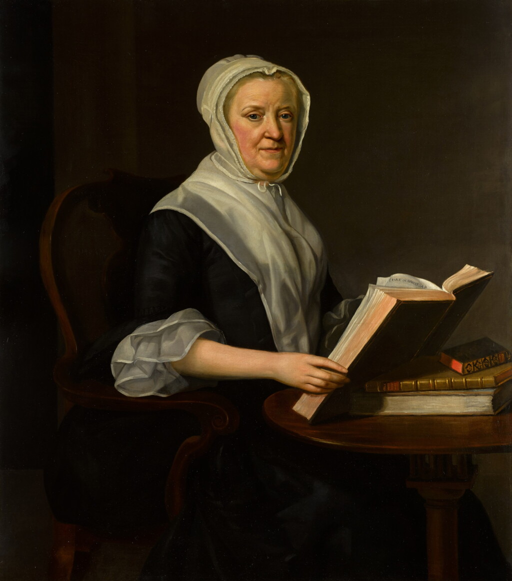View full screen - View 1 of Lot 80. A portrait of an elderly lady, three-quarter-length, wearing a dress, trimmed with white silk, and a cap, seated at a table with books.