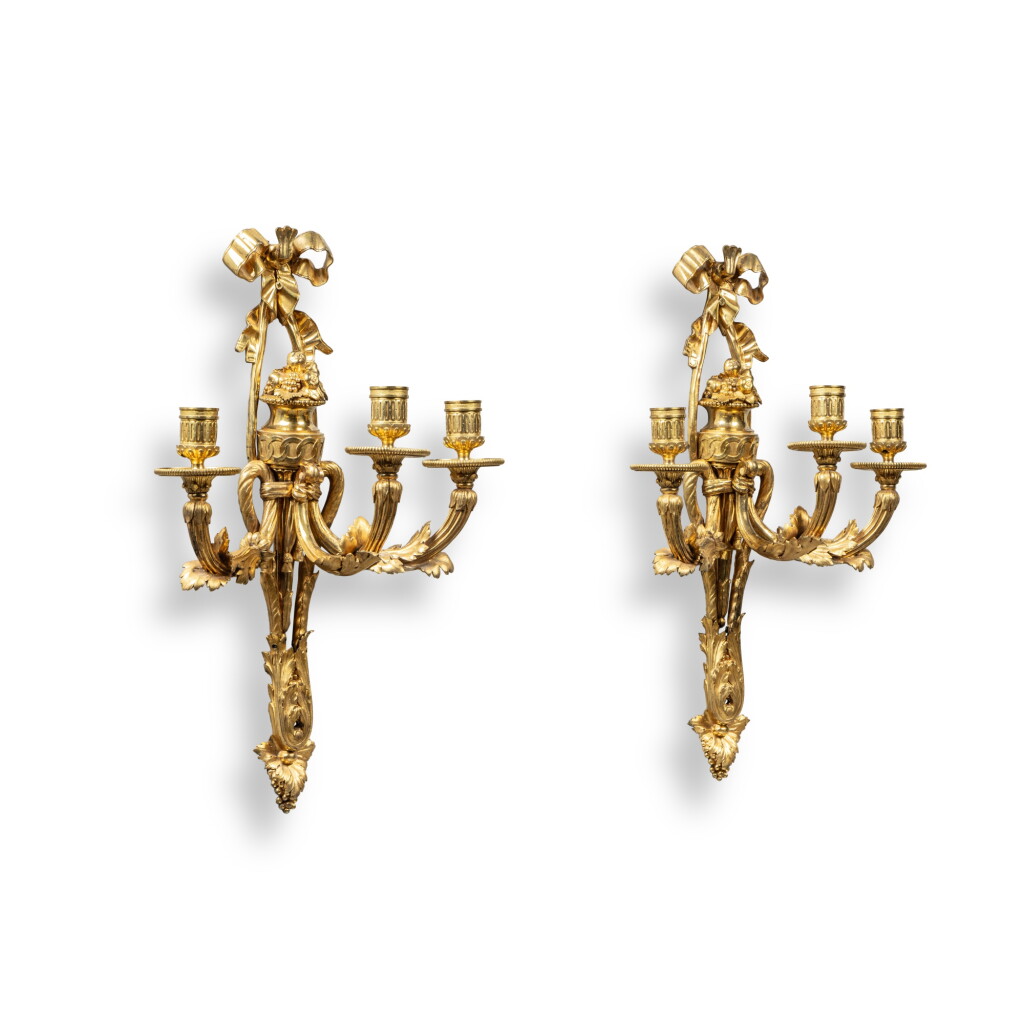 View full screen - View 1 of Lot 27. A pair of late Louis XV gilt-bronze three-light wall lights, circa 1775, after a model attributed to Quentin-Claude Pitoin and Dambière.