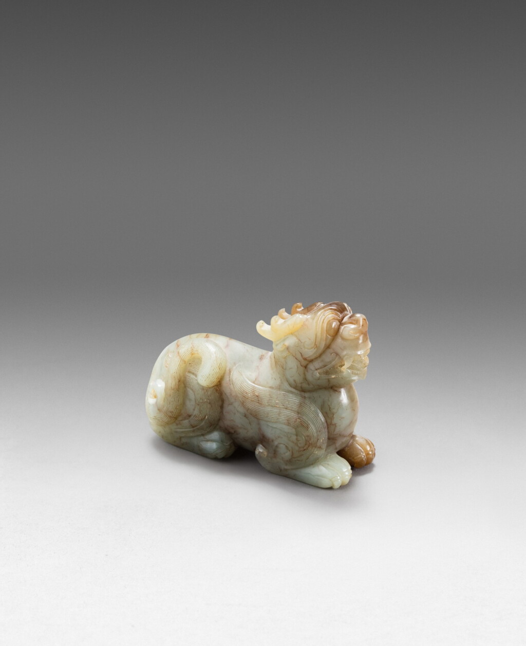 View full screen - View 1 of Lot 195. A grey and brown jade recumbent mythical beast Qing dynasty, 17th-18th century | 清十七至十八世紀 玉雕瑞獸把件.