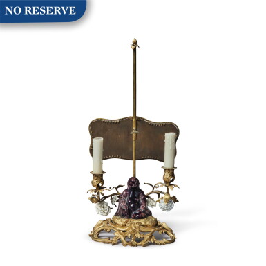 View full screen - View 1 of Lot 248. A Louis XV Two-Light Gilt Bronze Reading Candelabra with a Chinese Porcelain Figure of a Magot and White French Porcelain Flowers, Circa 1830.