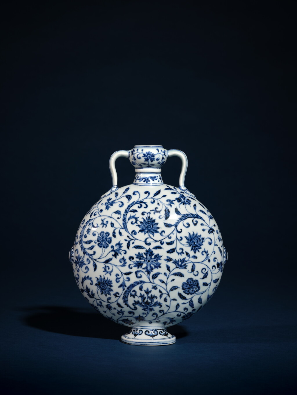View full screen - View 1 of Lot 301. A superb and exceptionally rare blue and white 'floral' moon flask, Ming dynasty, Yongle period | 明永樂 青花纏枝花卉紋雙耳扁壺.