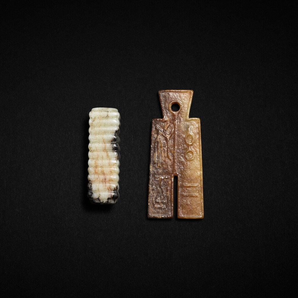 View full screen - View 1 of Lot 552. An inscribed jade 'bubi' pendant and a small white and russet jade cong, Ming dynasty or earlier | 明或更早 青玉布幣形珮及黑白玉琮形墜飾 .