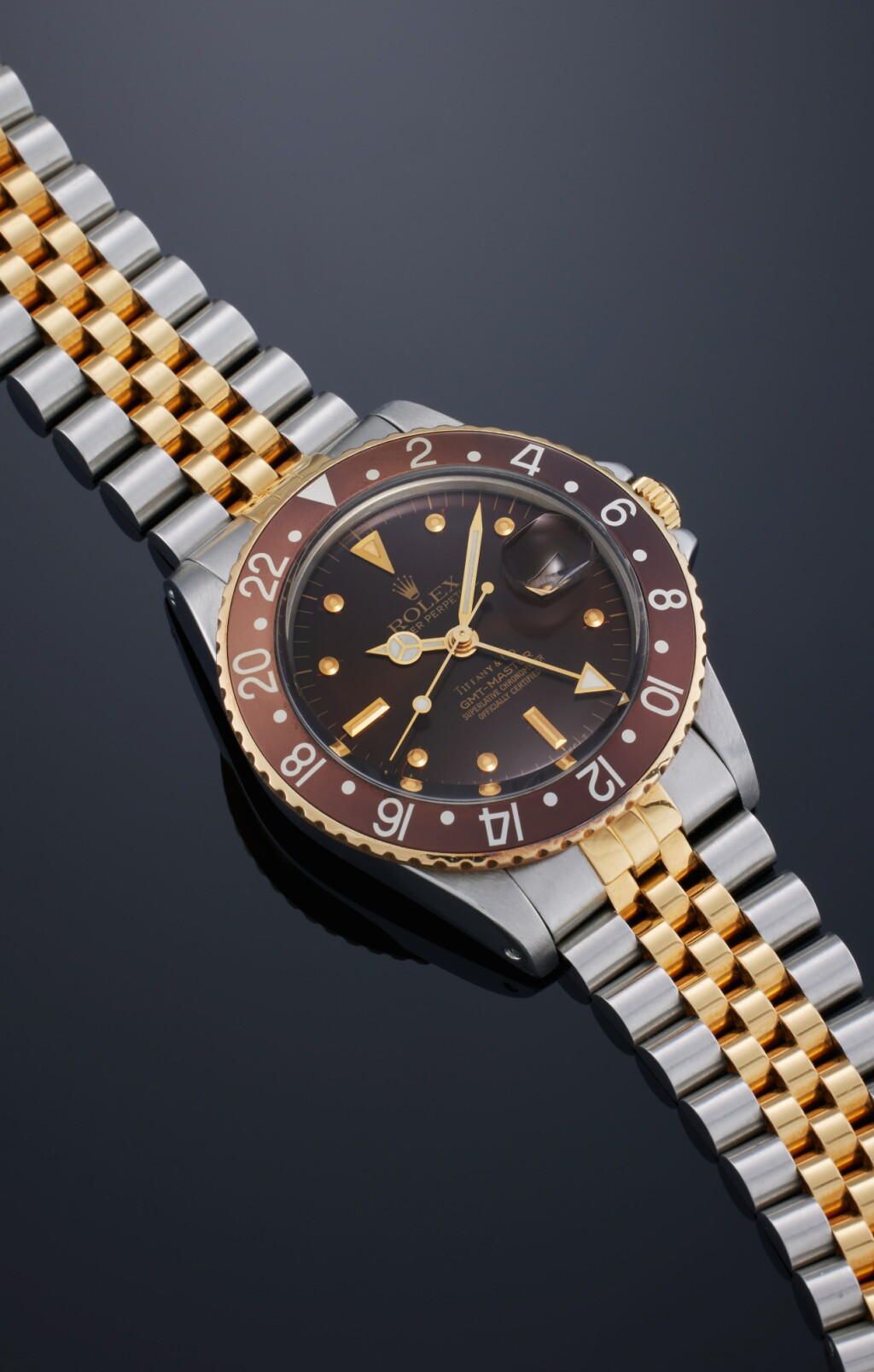 View full screen - View 1 of Lot 38. Reference 16753 GMT Master ‘Root Beer’ | Retailed by Tiffany & Co.: A stainless steel and yellow gold automatic dual time wristwatch with date, bracelet, and nipple dial, Circa 1986.