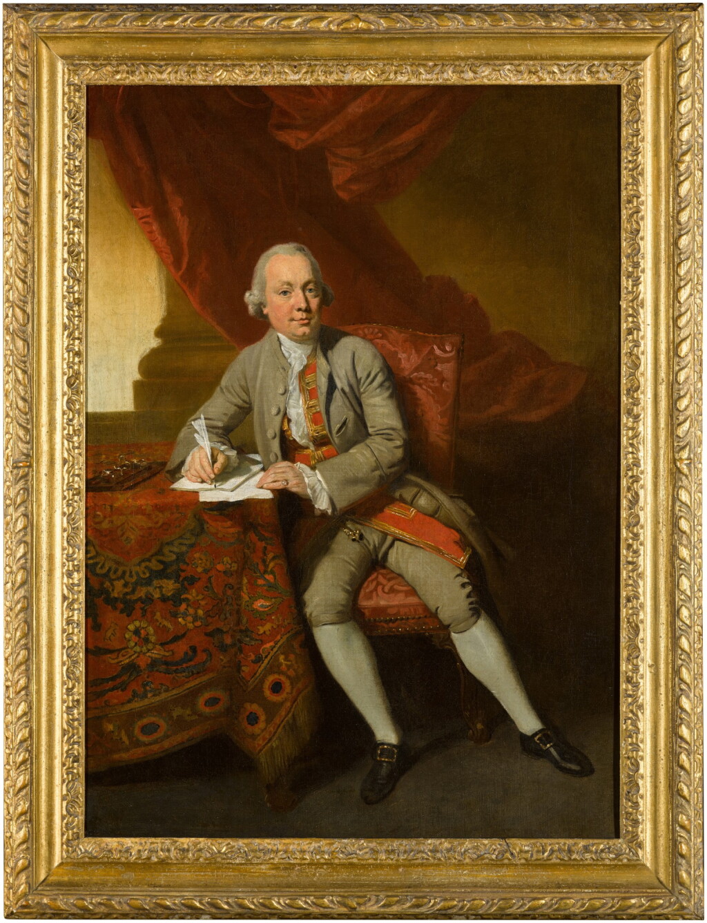 View full screen - View 1 of Lot 57. Portrait of a gentleman, full-length, seated by a table, wearing a coat and breeches with a red and gold waistcoat, holding a quill.