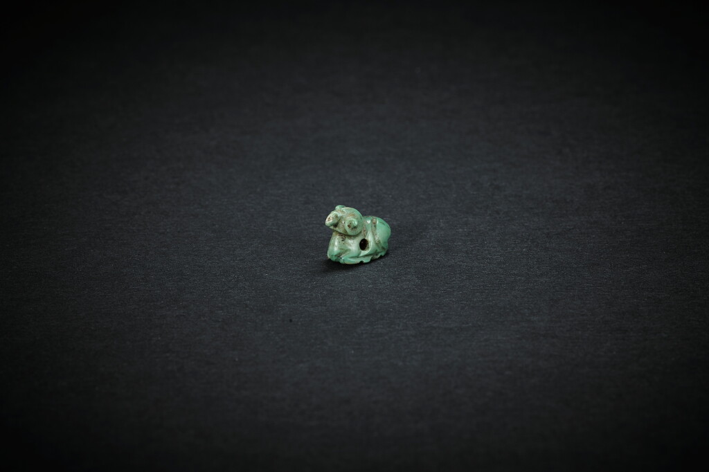 View full screen - View 1 of Lot 3837. A turquoise 'recumbent ram' pendant, Han dynasty | 漢 綠松石羊形佩.