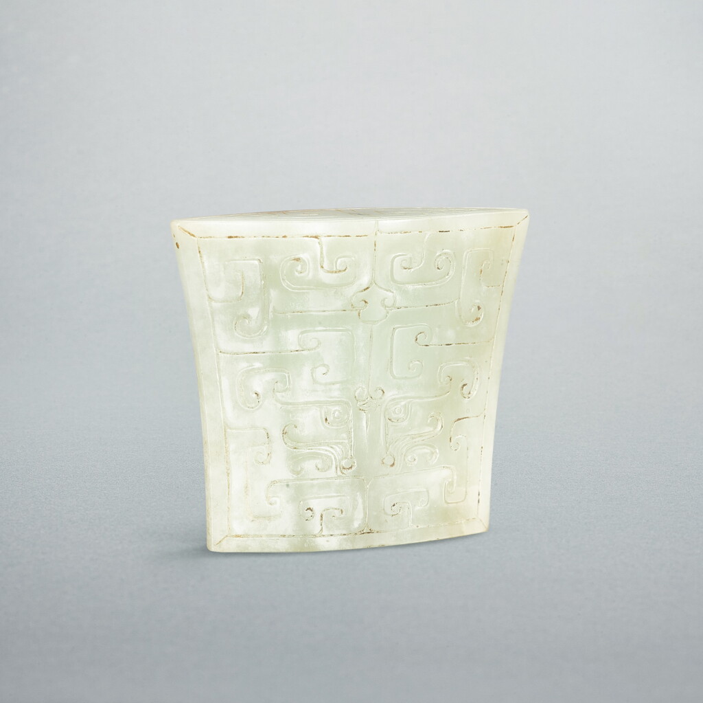 View full screen - View 1 of Lot 740. A pale celadon jade 'mask' scabbard chape, Eastern Zhou dynasty, Warring States period - Western Han dynasty | 東周戰國至西漢 青白玉獸面紋劍珌.