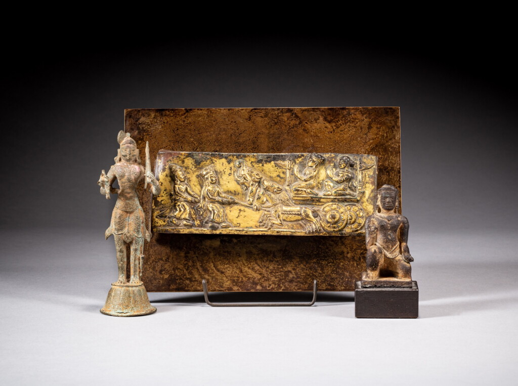 View full screen - View 1 of Lot 100. A gilt-copper plaque depicting Bhimaratharohana, a bronze standing figure and a stone figure of a kneeling deity, Nepal, 17th century | 尼泊爾 十七世紀 銅鎏金比瑪拉墖牌飾,銅鎏金人物立像及石雕佛座.