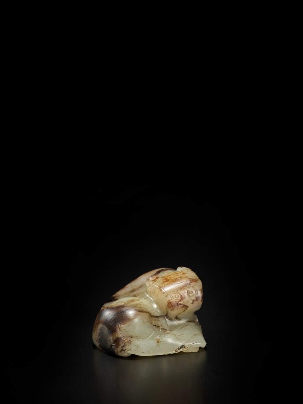 View full screen - View 1 of Lot 52. A pale green and brown jade figure of a tiger, Ming dynasty | 明 玉臥虎.