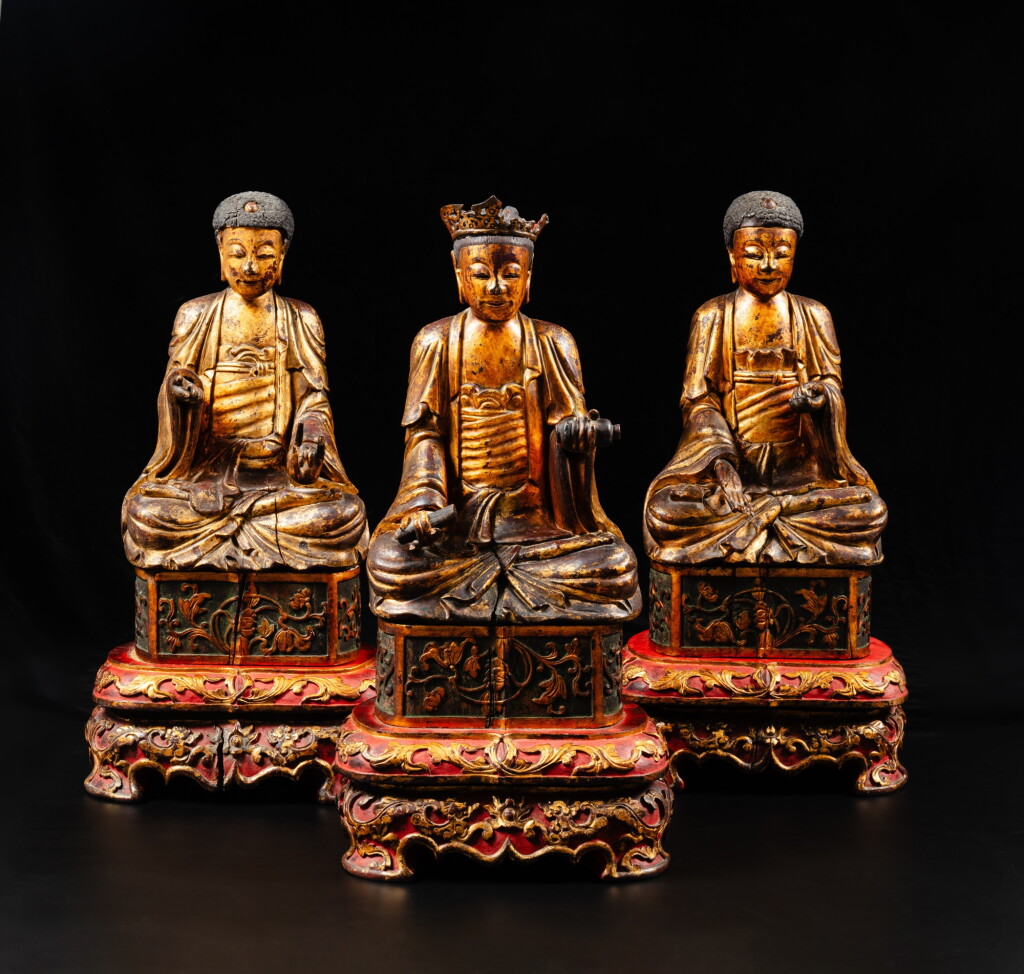 View full screen - View 1 of Lot 214. A set of three gilt-lacquer wood figures of Buddha, Qing dynasty, 19th century | 清十九世紀 漆金木雕佛坐像 一組三件.