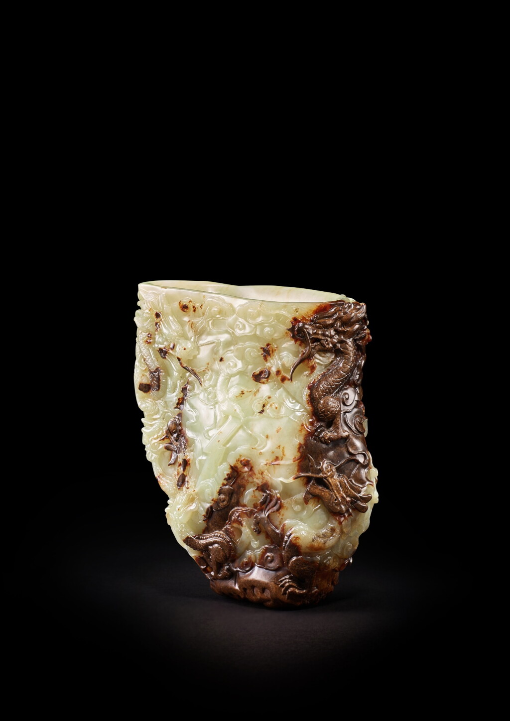 View full screen - View 1 of Lot 3642. A yellow and russet jade 'nine dragon' rhyton, Qing dynasty, 18th century | 清十八世紀 黃玉帶皮雕九龍戲珠角盃.