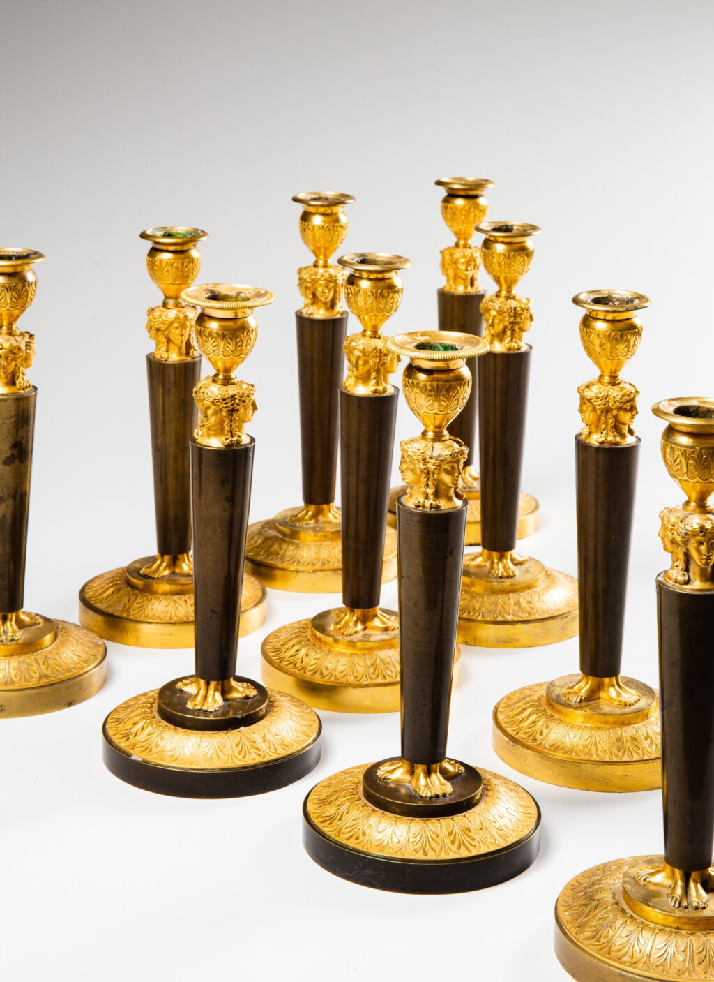 View full screen - View 1 of Lot 70. An Empire suite of ten patinated and gilt-bronze candlesticks, the model attributed to Claude Galle (1759-1815), circa 1805 | Suite de dix flambeaux en bronze doré et patiné d'époque Empire, le modèle attribué à Claude Galle (1759-1815), vers 1805.