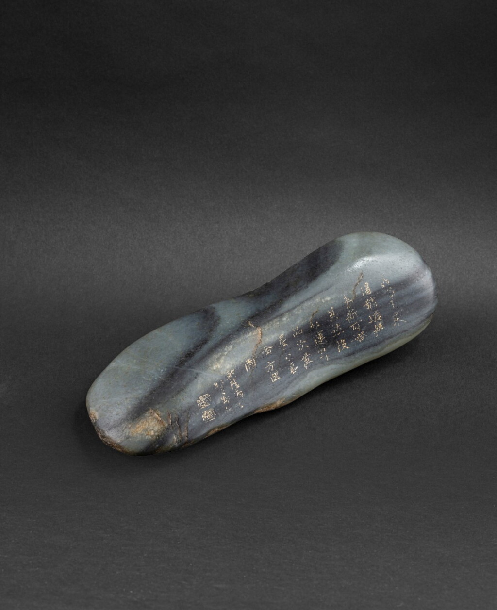 View full screen - View 1 of Lot 166. Galet en jade veiné gris formant repose-pinceaux et inscrit d'un poème Dynastie Qing | 清 陰刻乾隆御製詩文隨形石擺件 | An inscribed grey jade pebble-formed brush rest, Qing Dynasty.