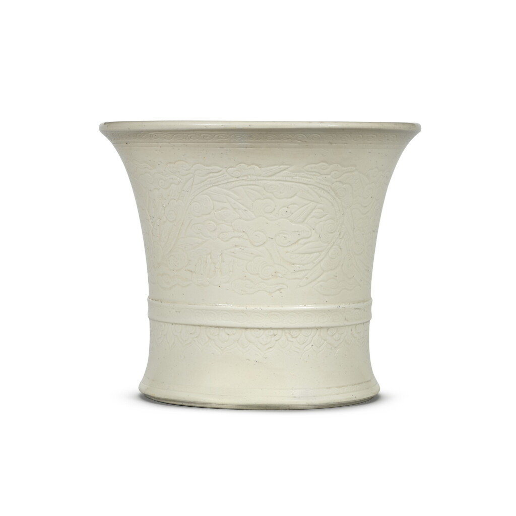 View full screen - View 1 of Lot 11. A white-glazed flaring cylindrical bruspot carved with a broad lingzhi scroll Qing dynasty, 17th century | 清十七世紀 白釉刻靈芝紋筆筒.