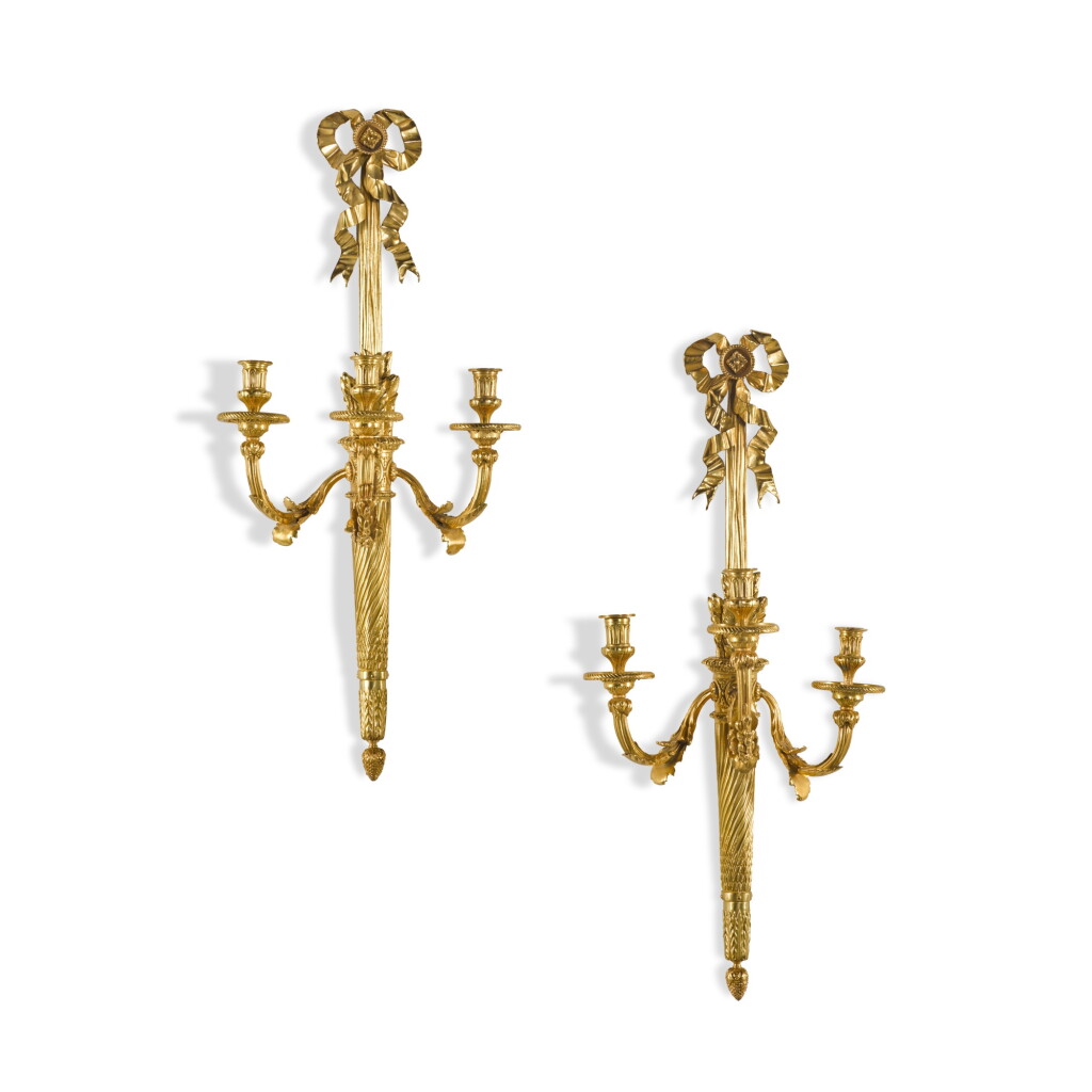 View full screen - View 1 of Lot 54. A pair of Louis XVI style gilt-bronze three-light wall appliques, 19th century.