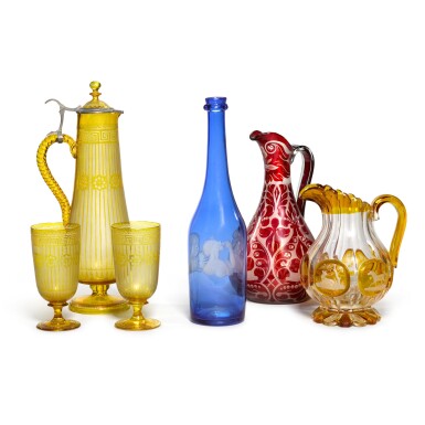 View full screen - View 1 of Lot 9. A Bohemian cut, amber-stained and engraved ewer, a ruby stained example, a blue stained carafe and an amber-stained ewer and goblets set, late 19th century.