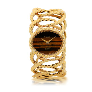 View full screen - View 1 of Lot 20. PIAGET | REFERENCE 9855 D35 RETAILED BY VAN CLEEF & ARPELS: A YELLOW GOLD CUFF WATCH WITH TIGER'S EYE DIAL, CIRCA 1970.