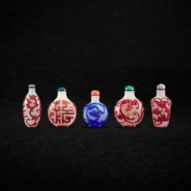 View full screen - View 1 of Lot 1006. Four red-overlay white glass snuff bottles and a blue-overlay white glass snuff bottles, Qing dynasty, 18th - 19th century | 清十八至十九世紀 霏雪地套紅料螭龍紋鼻煙壺四件 及 霏雪地套藍料螭龍鼻煙壺一件.