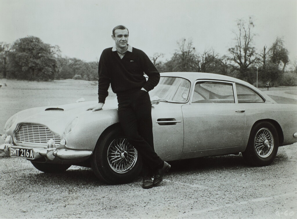 View full screen - View 1 of Lot 70. Sean Connery with Aston Martin DB5 During the Filming of 'Goldfinger', Stoke Park (horizontal).