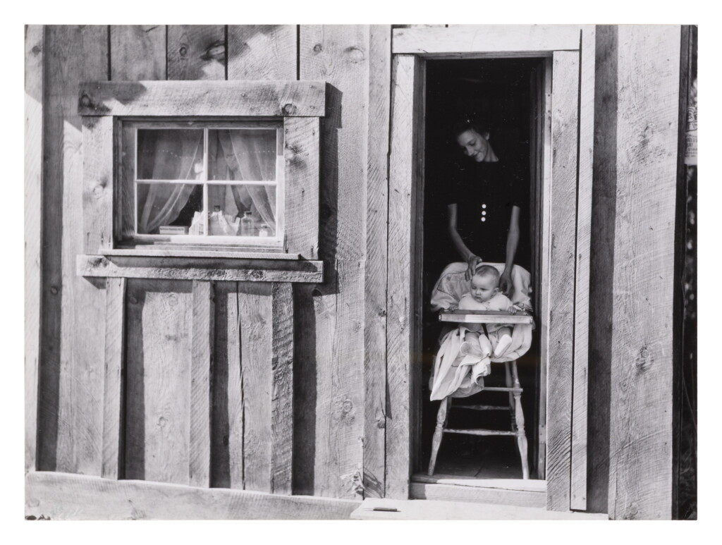 View full screen - View 1 of Lot 324. Wife and baby of president of Ola self-help sawmill co-op in doorway of their home, Gem County, Idaho.