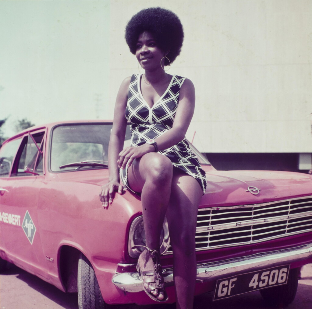 View full screen - View 1 of Lot 24. Woman posing on James Barnor's car, Accra, c.1970.