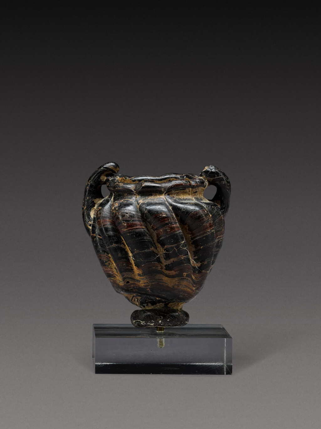 View full screen - View 1 of Lot 10. A Late Roman Black and Red Core-Formed Glass Cosmetic Jar, circa 5th/7th century A.D..