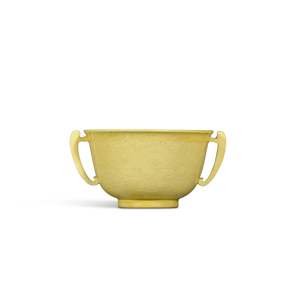 View full screen - View 1 of Lot 6. A fine incised yellow-glazed 'dragon' handled cup, Mark and period of Kangxi | 清康熙 黃釉暗刻雙龍戲珠紋雙耳小盃 《大清康熙年製》款.