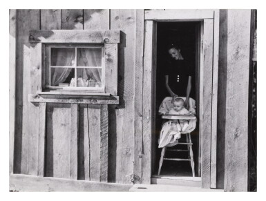 View full screen - View 1 of Lot 324. Wife and baby of president of Ola self-help sawmill co-op in doorway of their home, Gem County, Idaho.