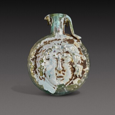 View full screen - View 1 of Lot 1. A Roman Pale Green Mould-Blown Janiform Glass Flask, circa 1st/2nd century A.D..