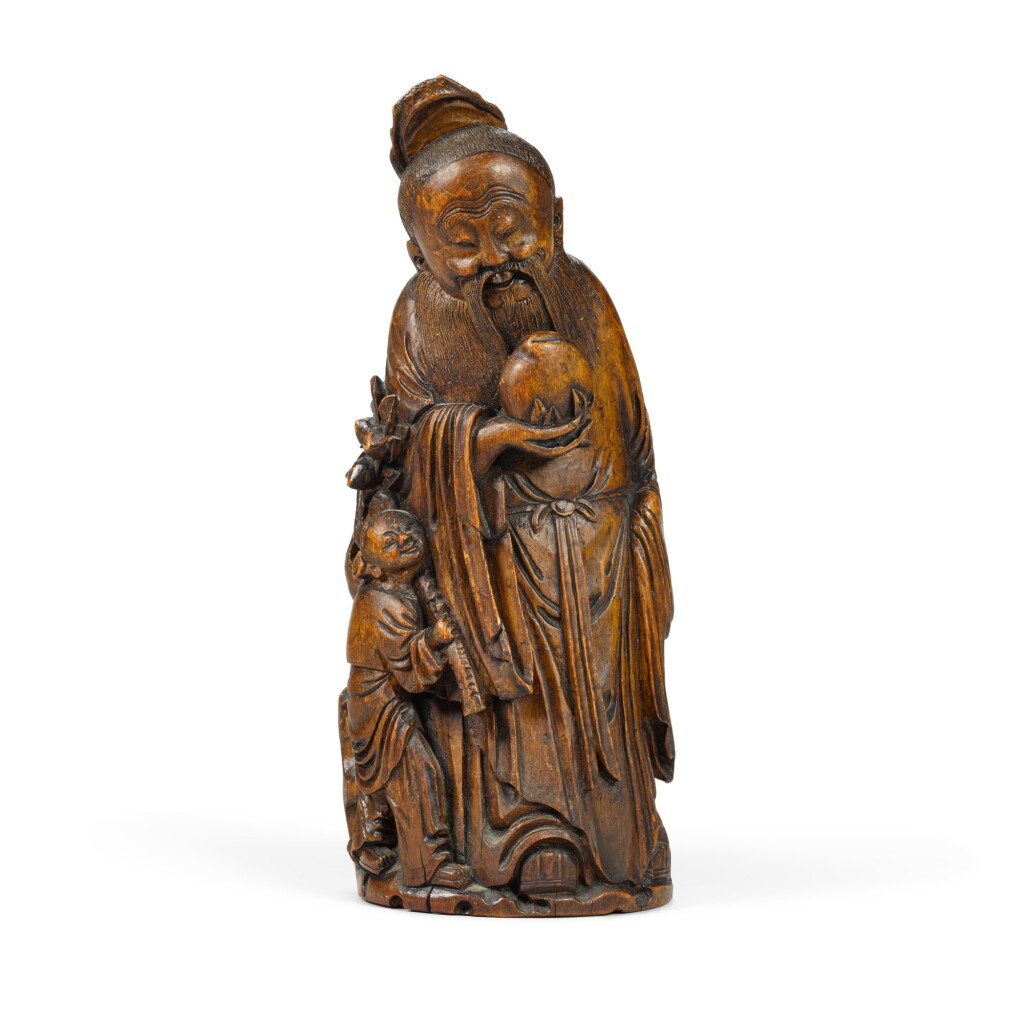 View full screen - View 1 of Lot 29. A large carved bamboo figure of Shoulao standing holding a peach with an attendant at his side Qing dynasty, 17th/18th century | 清十七/十八世紀 竹雕壽老.