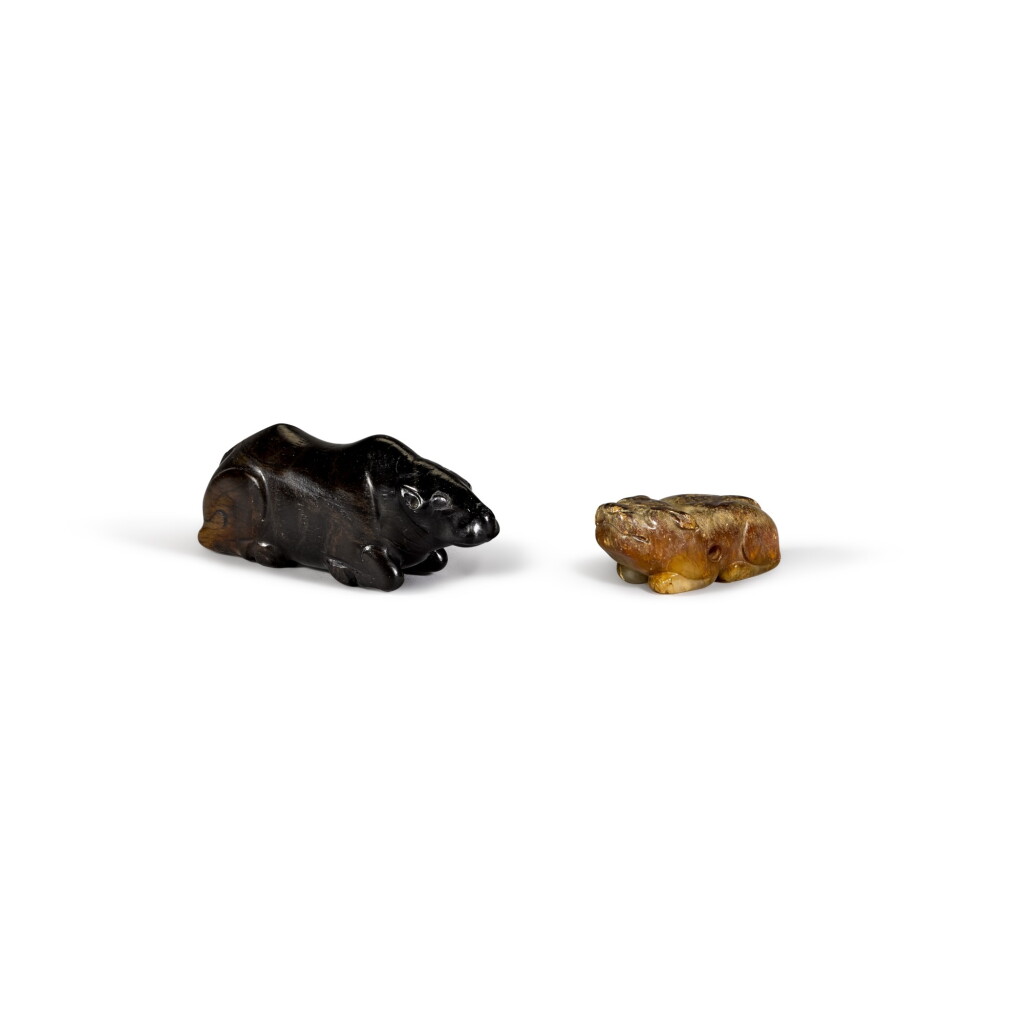 View full screen - View 1 of Lot 33. A black stone figure of a recumbent buffalo and a mottled jade figure of a small bear/dog Qing dynasty | 清 黑石臥牛 及 青玉犬 一組兩件.