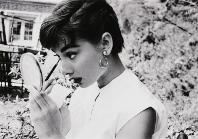 View full screen - View 1 of Lot 137. Audrey Hepburn putting on makeup in mirror, 1953.